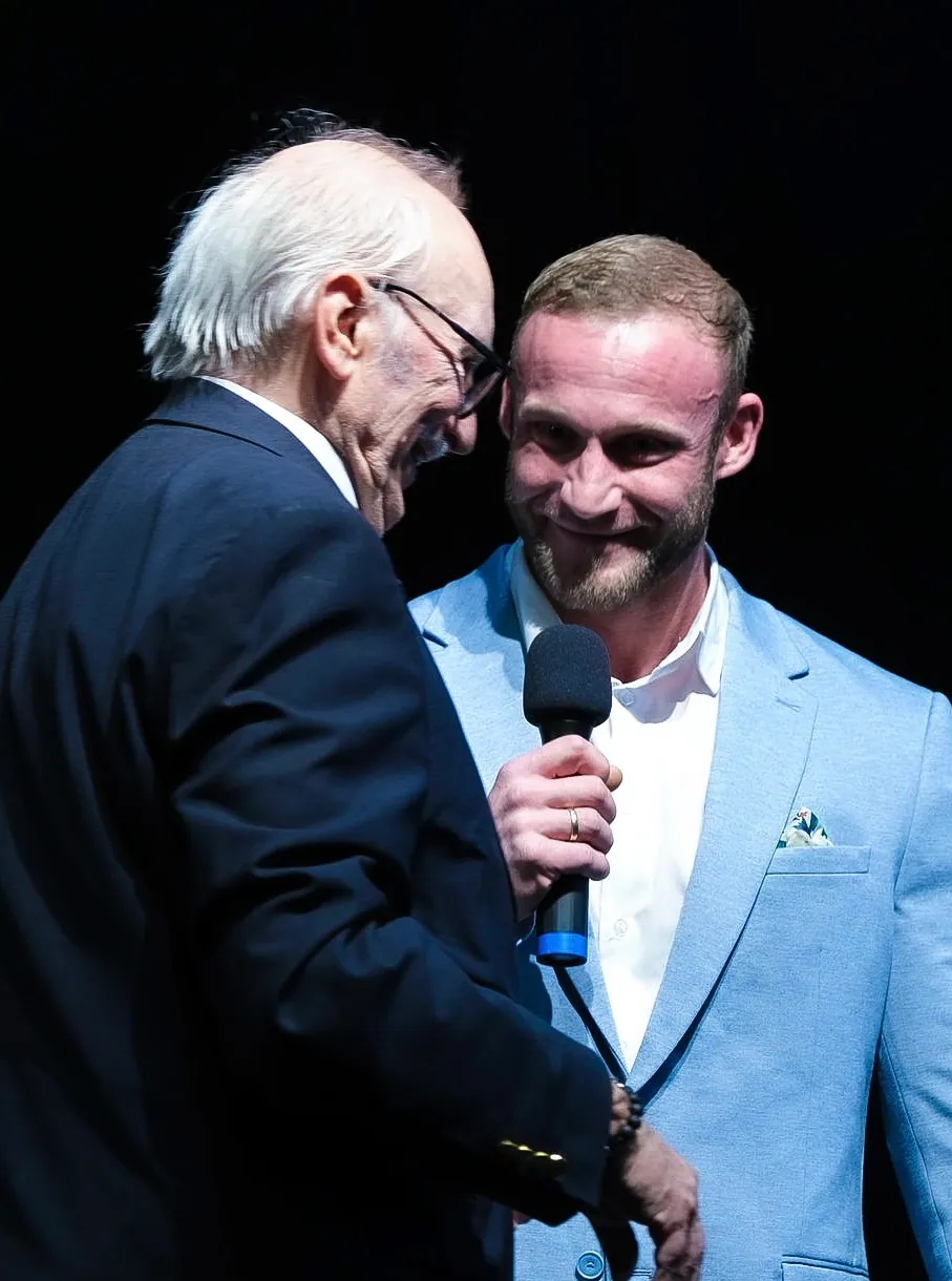 Dominik Dörfl conducting a stage interview with a microphone at an evening event