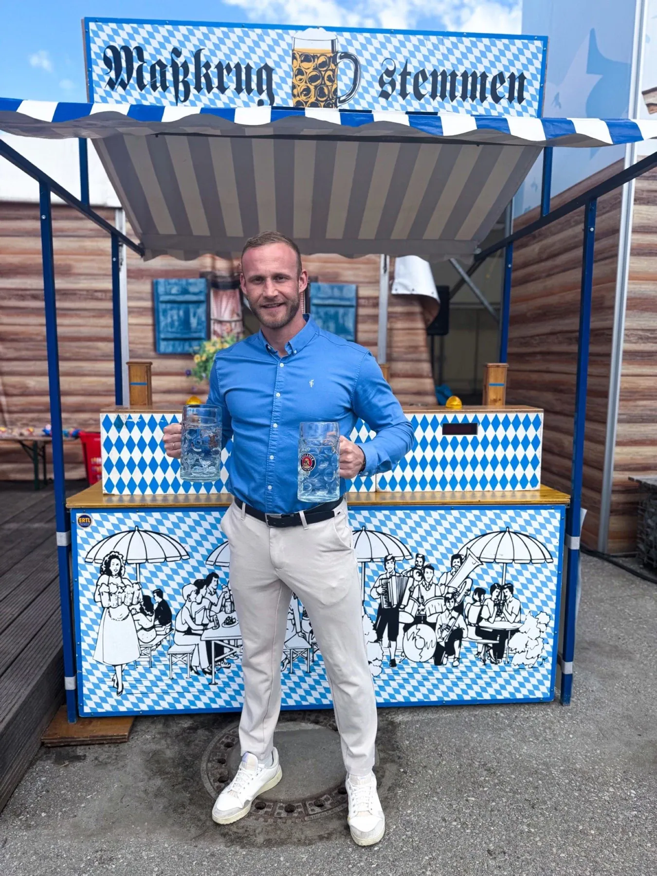 Dominik Dörfl mit zwei Maßkrügen vor einem Maßkrugstemmen-Stand
