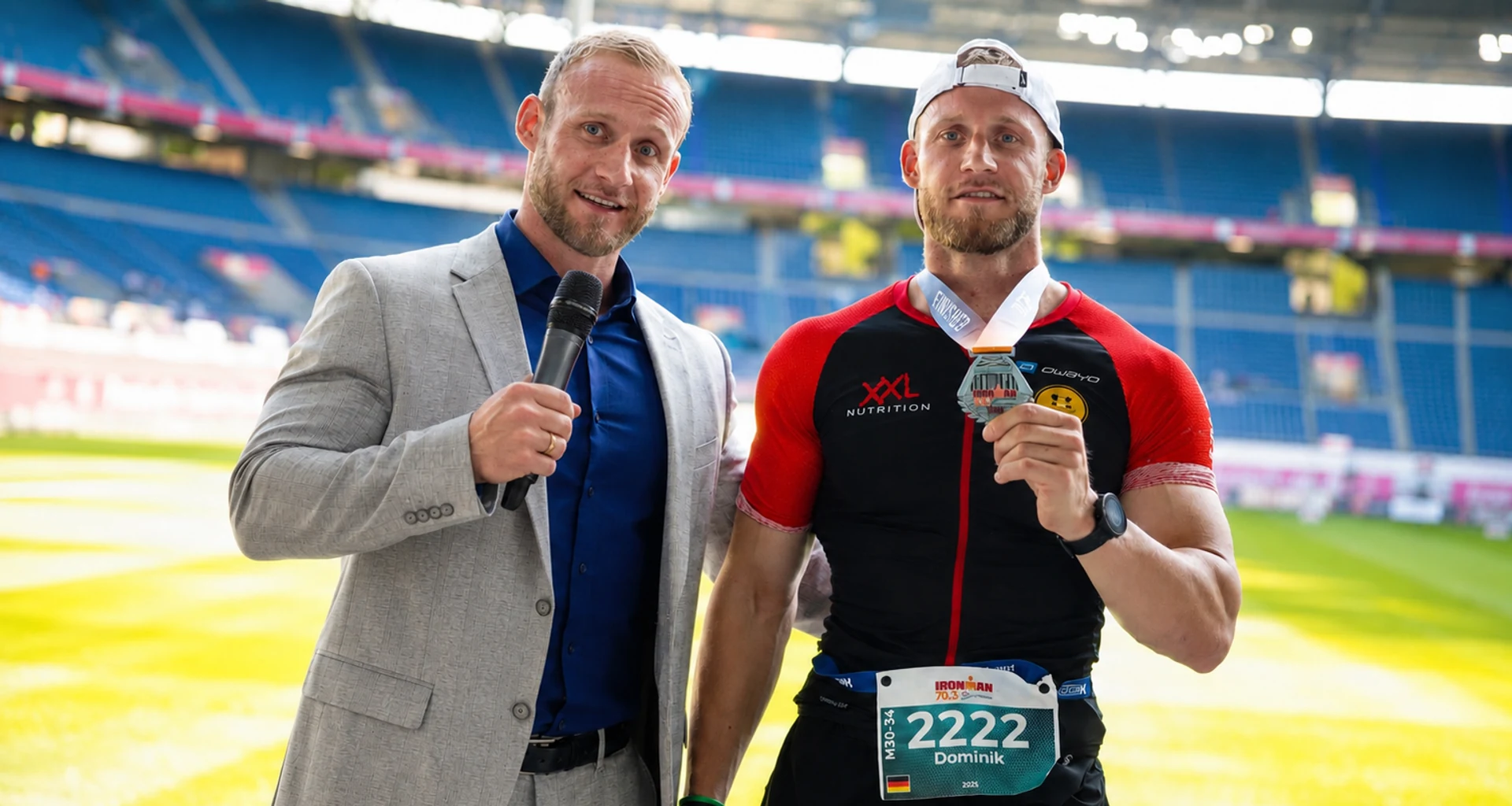 Dominik Dörfl als Ironman-Finisher mit Medaille bei einem Interview im Stadion