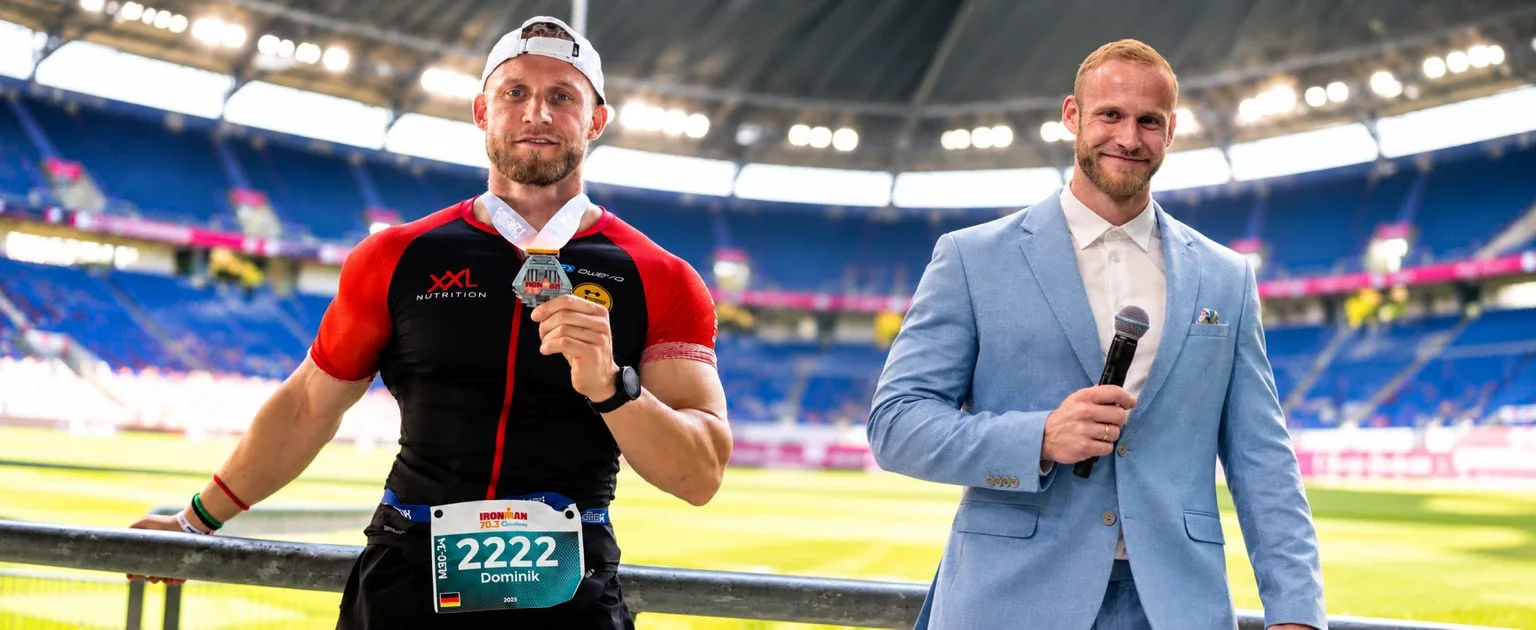 Dominik Dörfl zweifach im Stadion: als Ironman-70.3-Finisher mit Medaille und im Anzug als Moderator