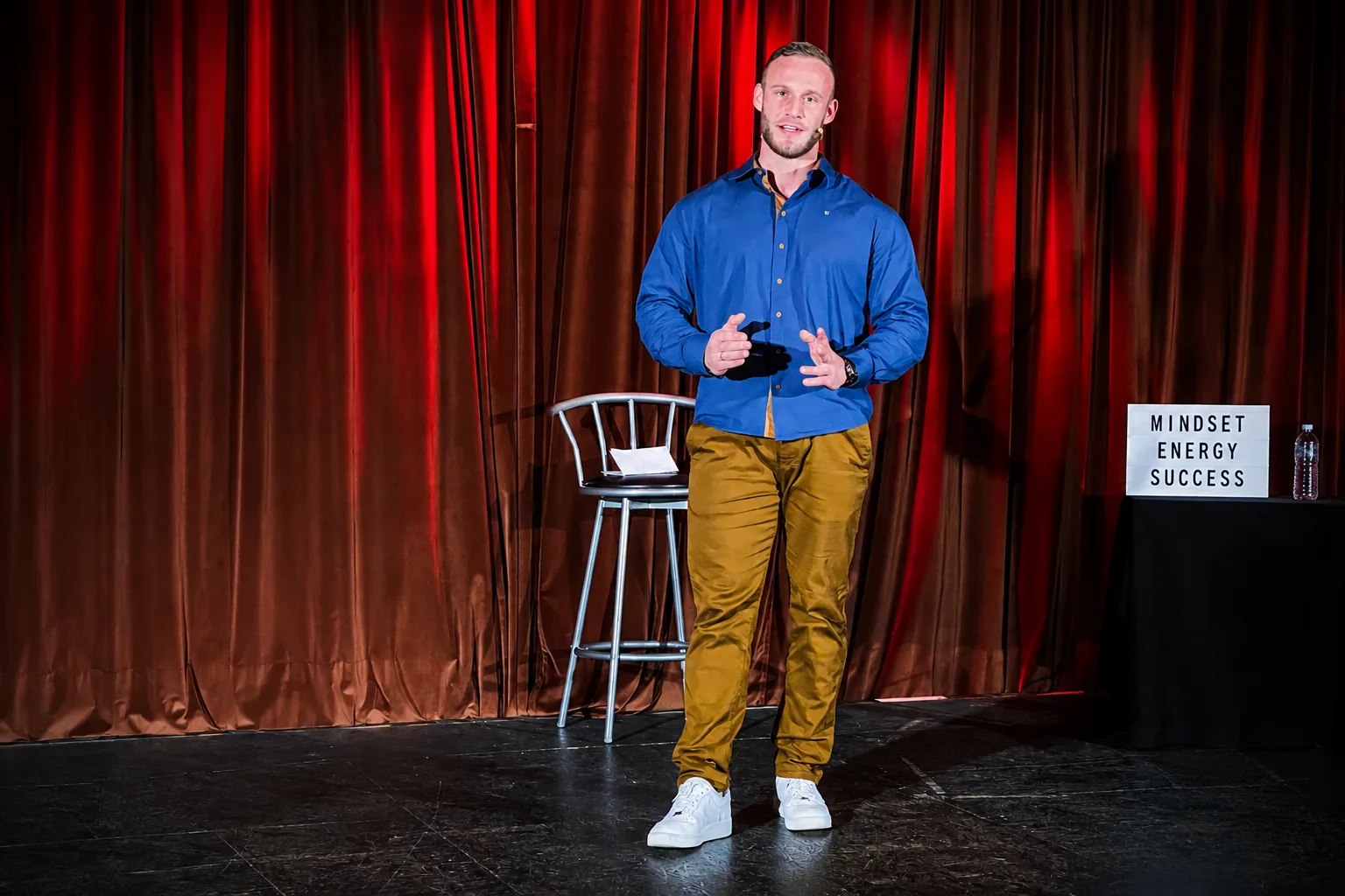 Dominik Dörfl speaking on stage in front of a red curtain