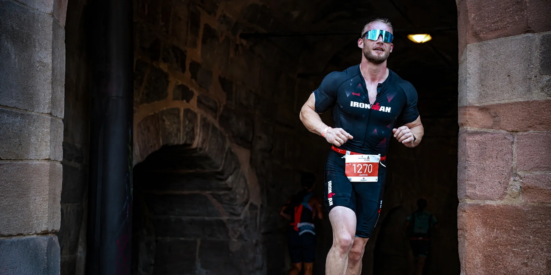 Dominik Dörfl, personal trainer in Nuremberg, crossing the finish line in his Ironman kit