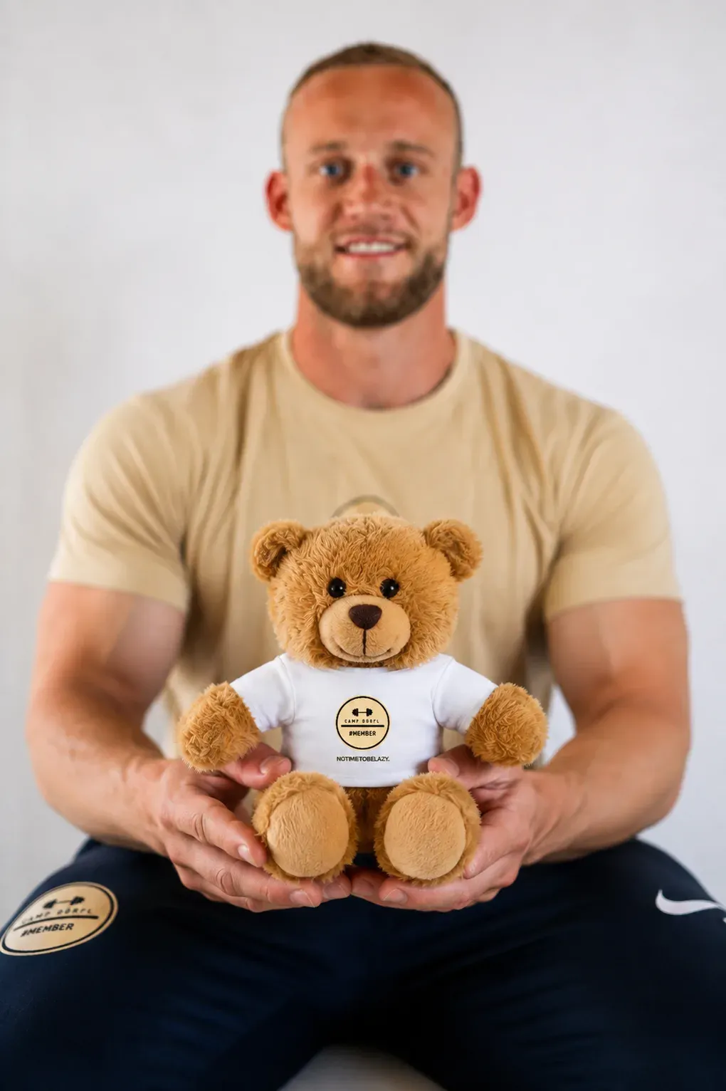 Buddy Dörfl, a teddy bear in a white Camp Dörfl shirt, held in two hands